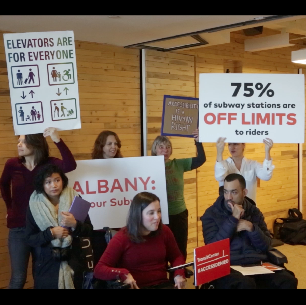 activists carry posters that read "75% of subway stations are off limits to riders" and "elevators are for everyone"